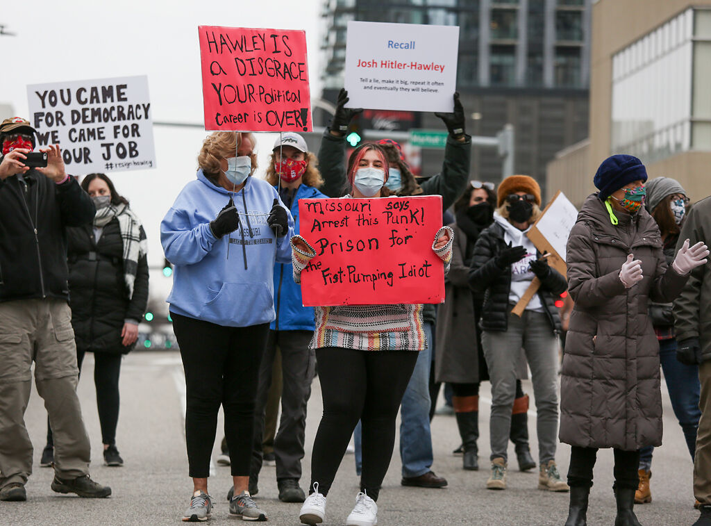 Janet Beltz, center left, and her granddaughter Payton Beltz listen to speakers while holding signs